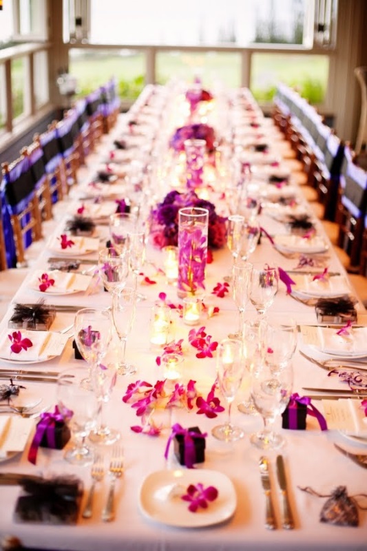 A bold white and purple wedding tablescape with bold purple blooms and napkins, candles and white linens is very elegant and refined