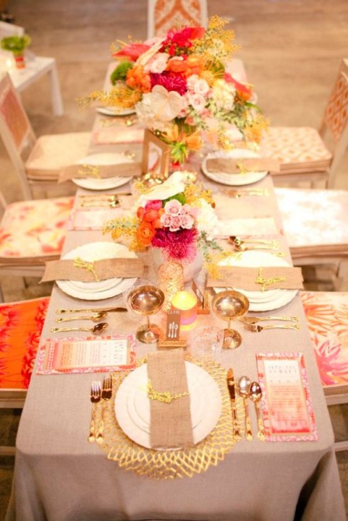 an elegant and colorful wedding tablescape with bold florals and gold chargers, gold cutlery and goblets looks very refined