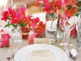a tropical wedding tablescape with neutral linens, bold red and pink florals and neutral cards and cutlery