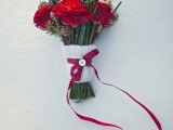 a white knit wrap with a red bow and a button on top is a great and cozy idea to accent your winter wedding bouquet