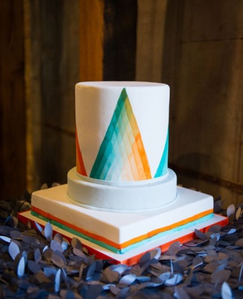 a round wedding cake with colorful ombre triangles painted on the surface looks outstanding and extra bold