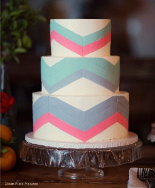 a round wedding cake decorated with squa, pink and blue lines forming chevrons looks bold and very unusual and will fit a modern wedding
