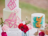 a gorgeous wedding cake with hot pink sugar shards that cover it and a white wedding cake with turquoise brushstrokes and gold triangles covering it is a lovely idea