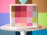 a square wedding cake with colorful squares painted on it and a pretty color block heart topper is a fresh idea for a modern wedding