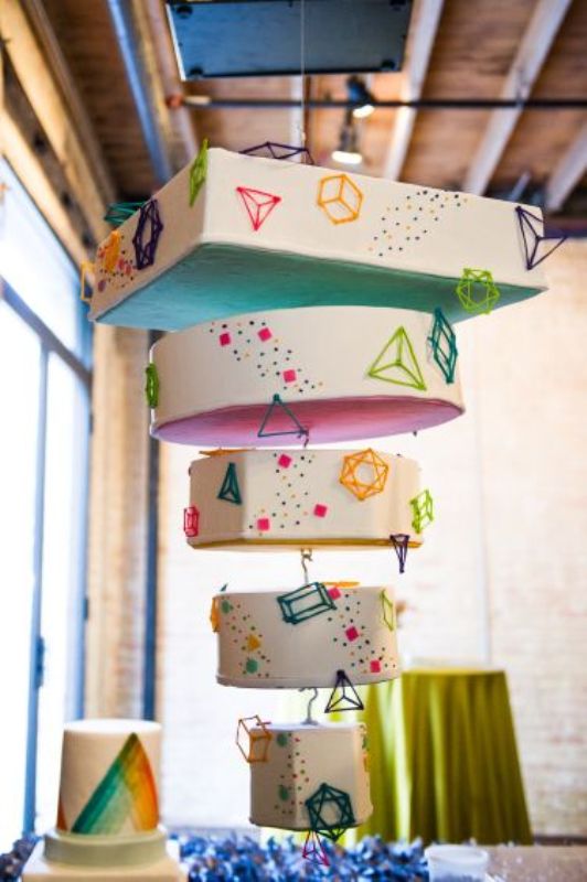 A unique suspended wedding cake with mismatching tiers covered with 3D triangles and squares, with colorful confetti and dots is a lovely idea for a modern wedding wedding and it makes a great impression
