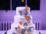 a round white wedding cake with colorful 3D triangles covering each tier is a stylish and cool idea for a modern wedding
