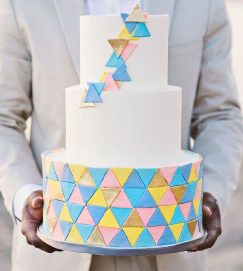 a round wedding cake decorated with colorful triangles and 3D triangles on the upper tiers is a lovely idea for a modern and colorful wedding