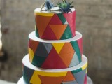 a colorful round wedding cake with bright triangles all over the cake, with a himmeli topper and thistles on top is a bright and fun idea for a wedding
