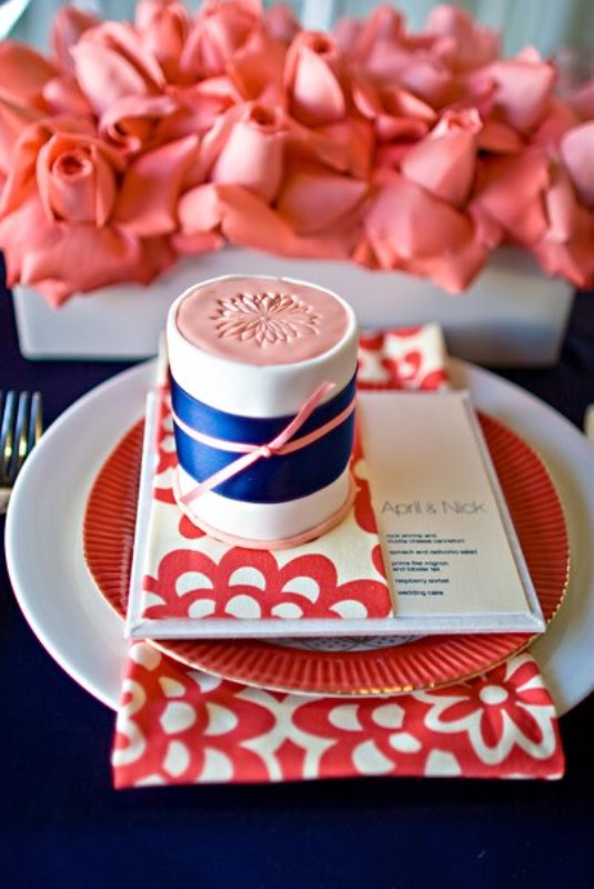 Coral blooms, a coral plate and menu and a coral and navy gift box with a bow for each place setting