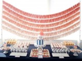 a navy dessert table with lots of sweets and a navy and coral wedding cake plus ombre coral wedding garlands over the table