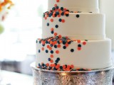 a white wedding cake with navy and coral piink polka dots for decor is an unobtrusive way to rock the color scheme