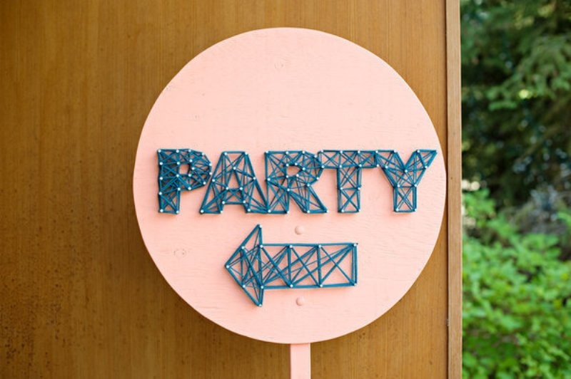 A fun circle coral sign with navy string art showing where to go is a very creative and trendy idea