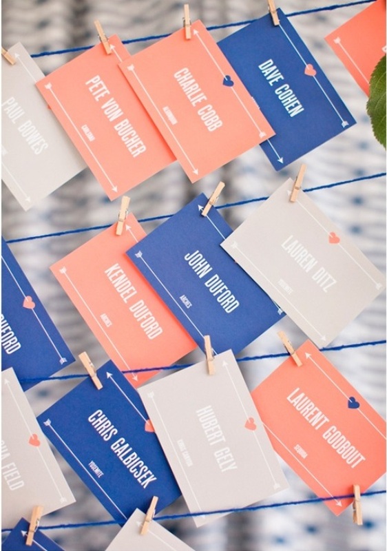 grey, coral and blue escort cards with white letters are a very fun idea of a wedding seating chart