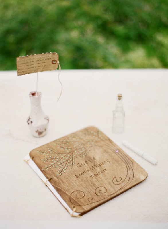 A creative guest book with a wooden cover, which is wood burnt, and usual pages inside