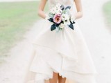 a statement A-line wedding dress with a turtleneck, short sleeves and a layered high low skirt with a train