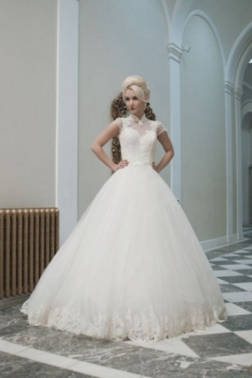 a wedding ballgown with a lace bodice with short sleeves, an illusion neckline and a full skirt with a lace trim