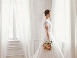 a romantic A-line wedding dress with short draped sleeves, a deep neckline, an embellished sash and a train