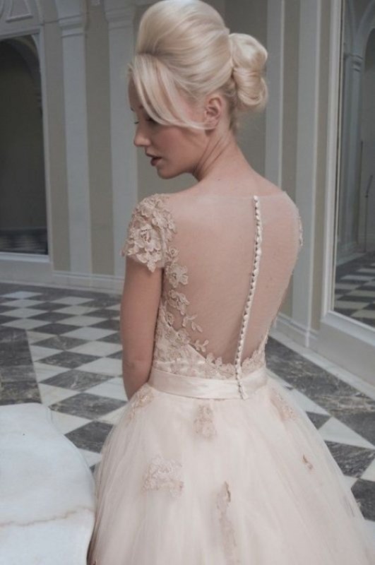 A nude lace wedding ballgown with a lace bodice, an illusion back on buttons and a full skirt with appliques