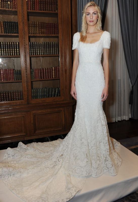 A fitting lace embellished wedding dress with short sleeves, a scoop neckline and a train