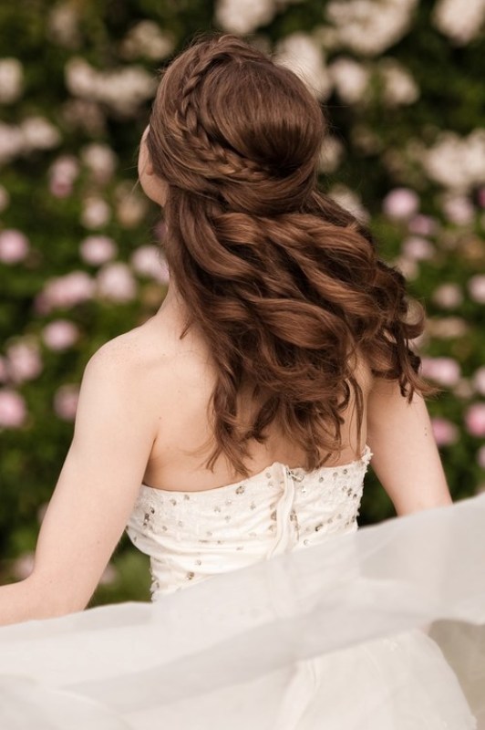 A romantic wedding half updo with a braid on one side and a twist on the second side, with waves down