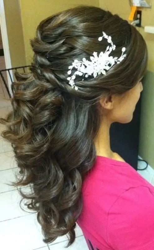 a breathtaking half updo with a twisted volume on top and waves going down plus a floral hairpiece for a formal bridal look