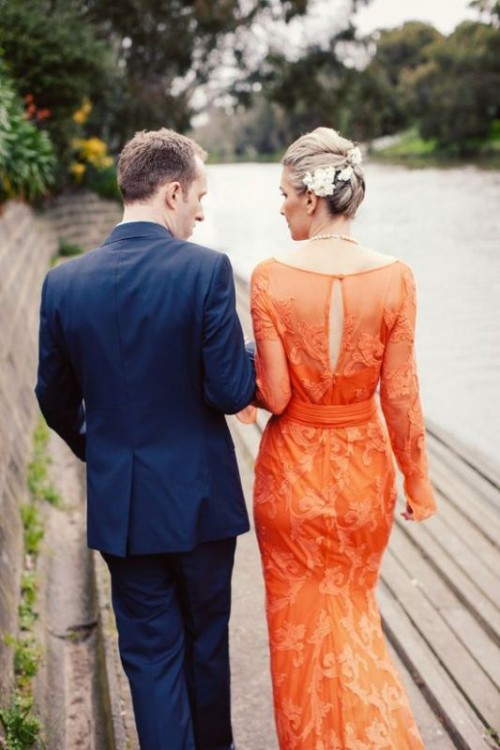 an orange sheath wedding dress with long sleeves, a cutout back and lace appliques is a statement with color