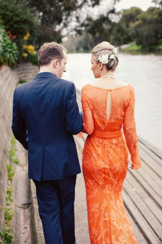 An orange sheath wedding dress with long sleeves, a cutout back and lace appliques is a statement with color