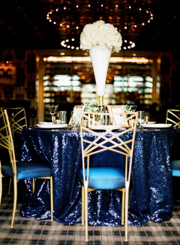 a midnight blue sequin tablecloth paired with white blooms and gold touches for a super chic look