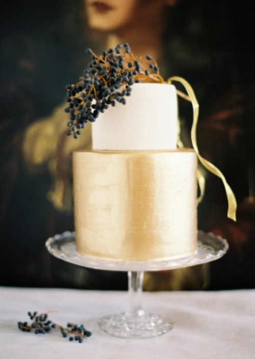 a shiny gold and white wedding cake topped with midnight blue berries for a contrasting touch