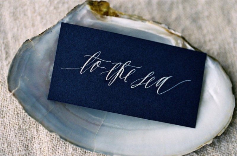 A midnight blue card in a seashell is a chic idea for a coastal wedding