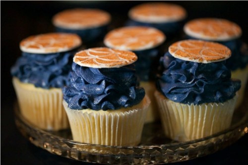 bright cupcakes with midnight blue cream and coral citrus toppers are a fun and bold idea for a wedding