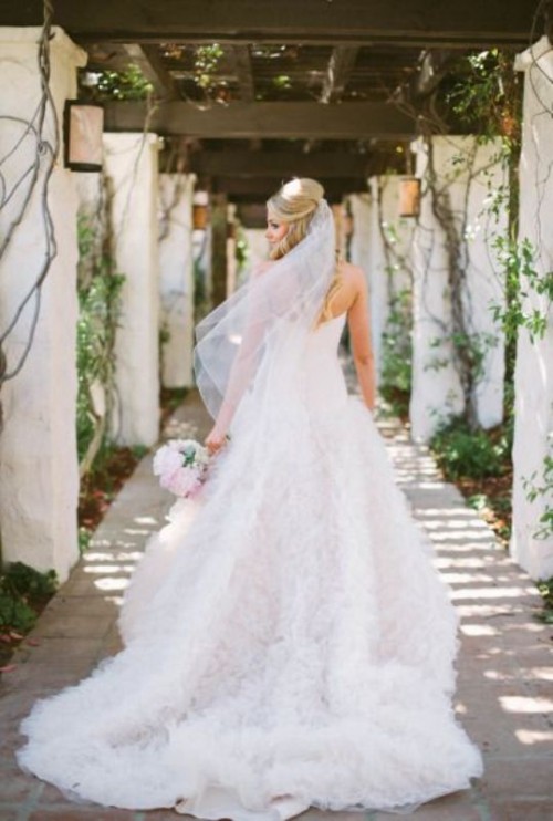 a princess wedding dress with a draped strapless bodice and a ruffle skirt with a train that catches an eye is wow