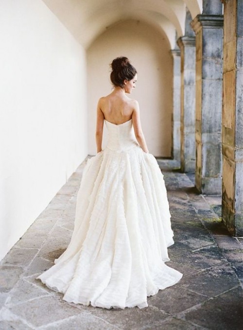a modern strapless princess style wedding gown with a plain bodice and a textural ruffl skirt with pleats and a train is amazing