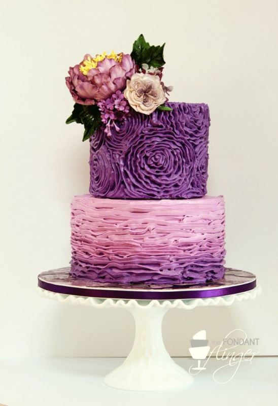 A textural purple wedding cake with a floral and an ombre ruffle tier plus fresh blooms and leaves on top