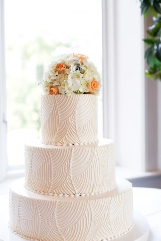 a white textural wedding cake with bright blooms on top is a cool idea for a modern wedding