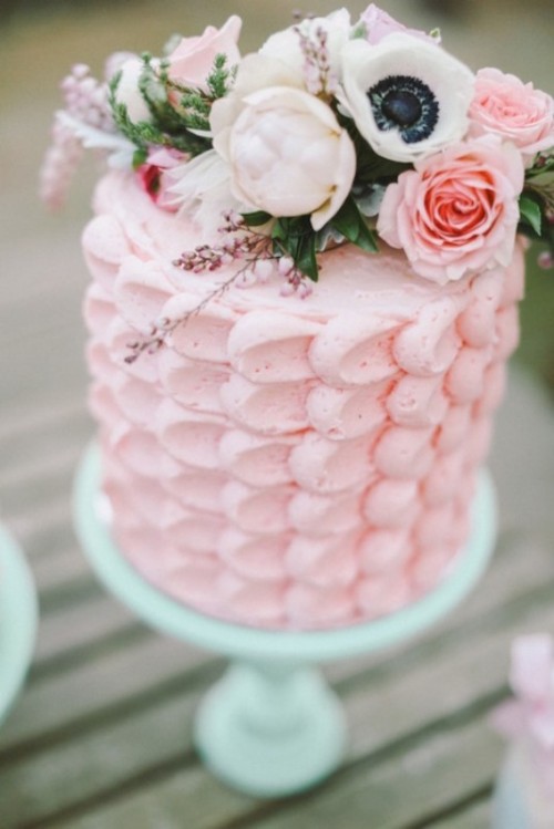 a pink textural wedding cake with white and pink blooms and greenery on top is very cute and chic