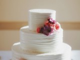 a white textural wedding cake decorated with bright fresh blooms for a simple and stylish wedding with a rustic touch