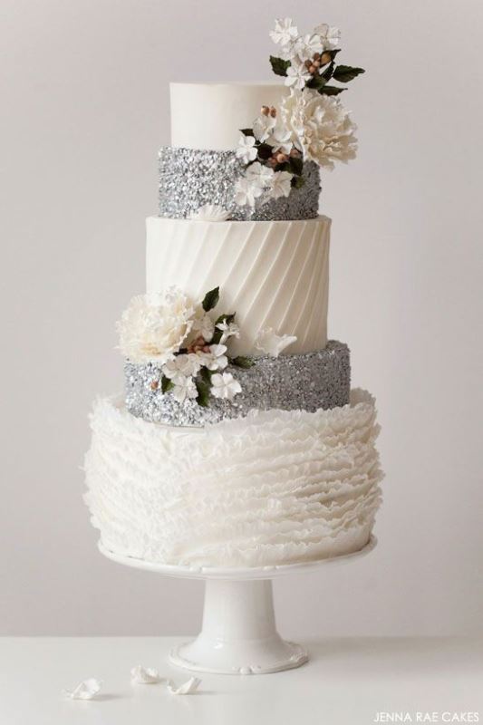 a white and silver wedding cake with striped, plain, glitter and ruffle tiers and sugar blooms and leaves