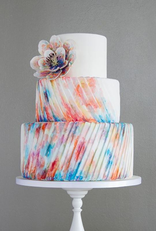 A colorful striped textural wedding cake with a large sugar flower is a bold idea for a modern wedding