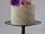 a white striped textural wedding cake with purple and pink sugar flowers is very bold and cool