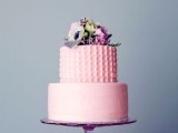 a light pink wedding cake with a textural patterned and a sleek tier plus fresh blooms on top