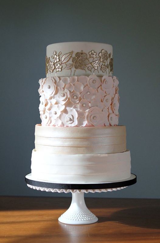 A refined wedding cake with striped tiers, floral ones in gold, white and pink