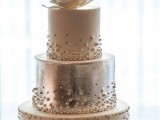 a white and silver textural wedding cake decorated with patterns, pearls and sugar blooms