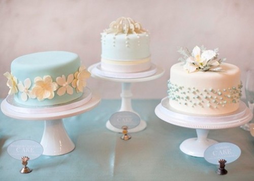 an assortment of three wedding cakes done in white and mint, with various kinds of decor and cool edible toppers