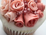 a cupcake with coral and blush sugar blooms on top plus edible beads is a gorgeous idea for a wedding with a color scheme