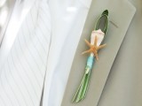 a seaside boutonniere of a seashell, a starfish, some grass and a ribbon is a cool idea for a coastal or beach wedding