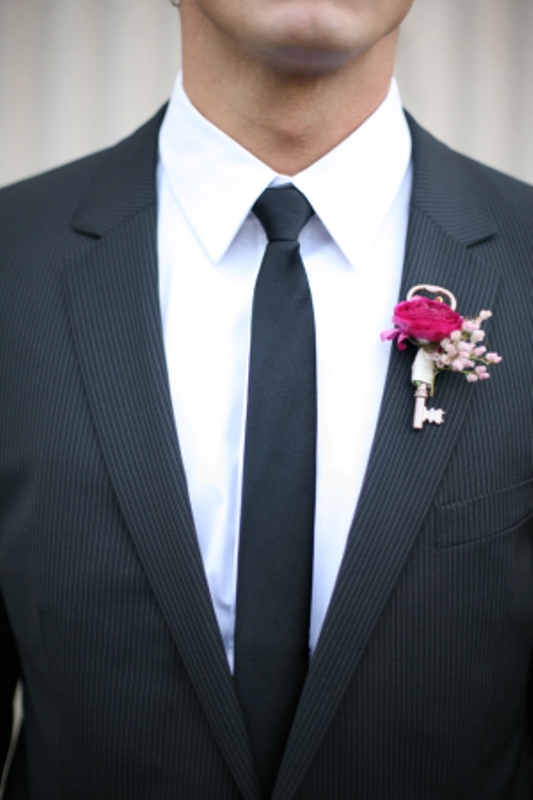 a cute and stylish boutonniere of a vintage key, a hot pink bloom and pink baby's breath is a very cool idea