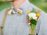 a unique summer woodland wedding boutonniere with a white bloom, billy balls, greenery, mushrooms and branches is pure fun