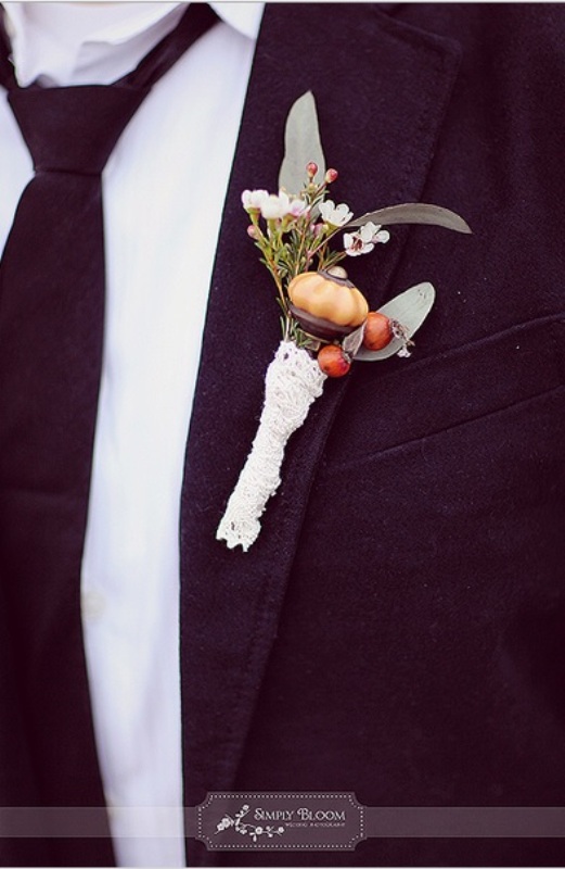 a unique fall boutonniere of greenery, white blooms and berries, a large amber piece and some lace wrap is a very interesting idea