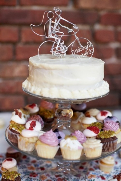 a white buttercream cake topped with a funny wire cake topper with the names of the couple is a cool and cute idea for a bike-lover wedding
